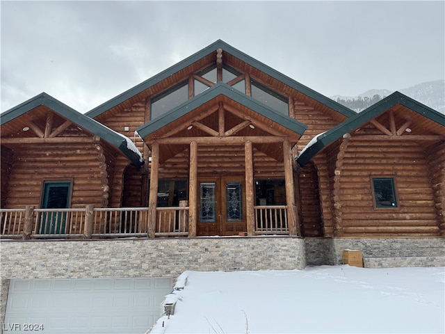 log cabin with covered porch and a garage