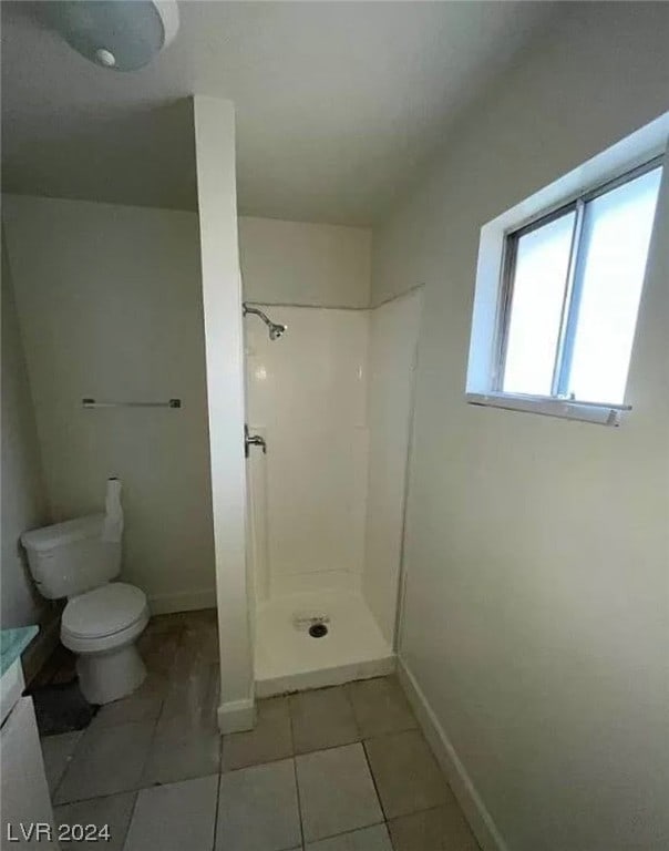 bathroom with a shower, tile floors, toilet, and vanity