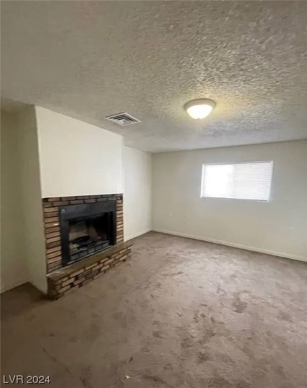 unfurnished living room featuring a brick fireplace, carpet flooring, and a textured ceiling