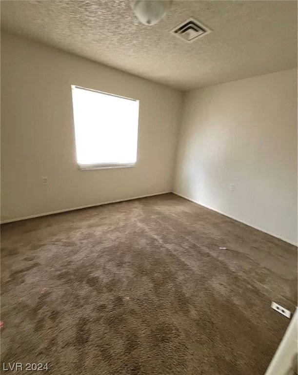 carpeted spare room featuring a textured ceiling