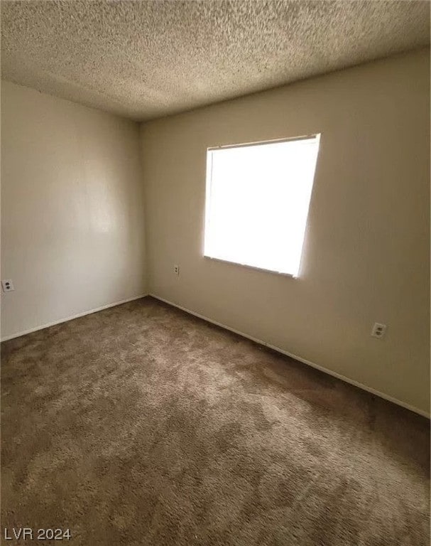 carpeted empty room with a textured ceiling