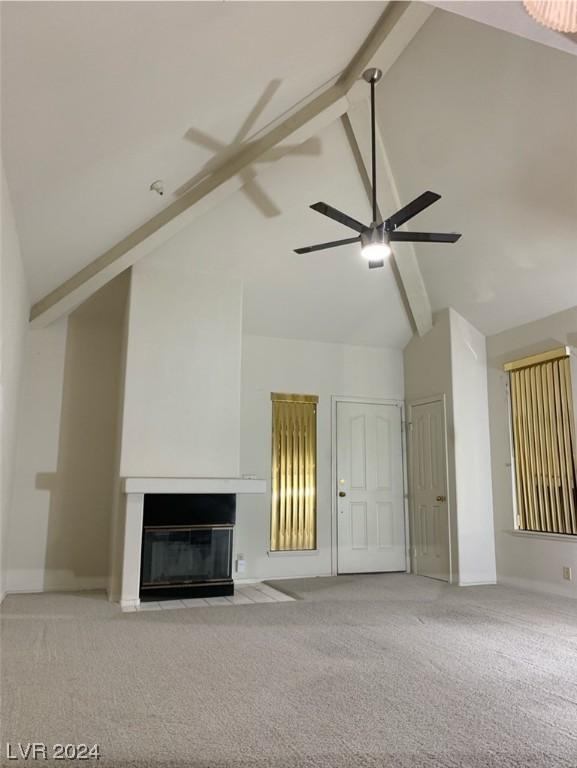 unfurnished living room with beam ceiling, ceiling fan, light colored carpet, and high vaulted ceiling