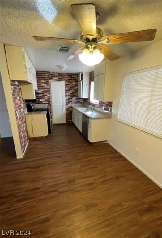 kitchen featuring stainless steel dishwasher, brick wall, ceiling fan, a textured ceiling, and dark hardwood / wood-style flooring