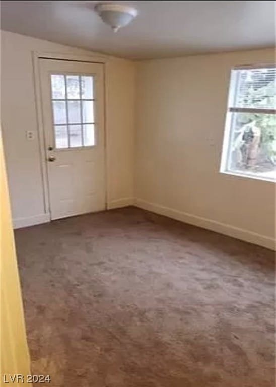 doorway featuring dark carpet and vaulted ceiling