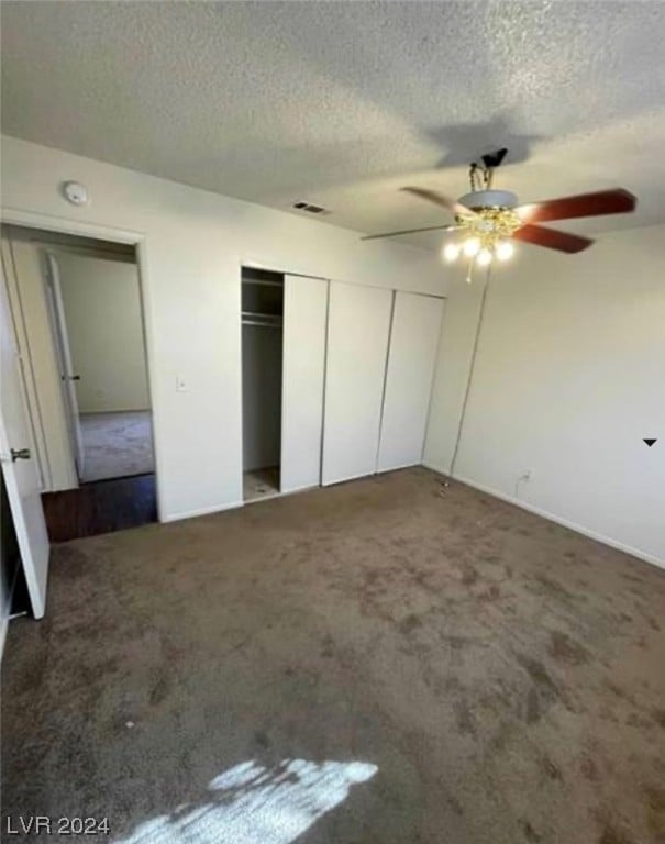 unfurnished bedroom with ceiling fan, dark carpet, and a textured ceiling