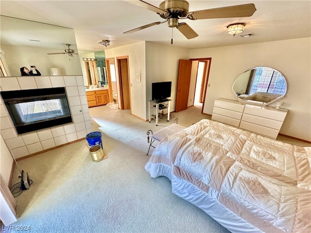 carpeted bedroom with a fireplace, ensuite bath, and ceiling fan