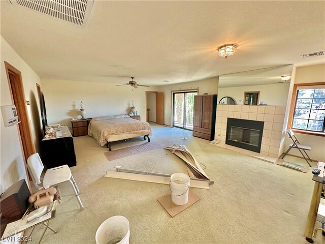 bedroom featuring multiple windows, a tiled fireplace, ceiling fan, and carpet floors