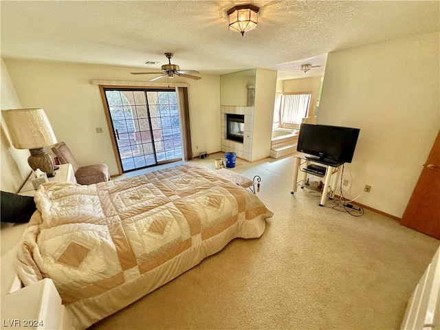 carpeted bedroom featuring multiple windows, a fireplace, a textured ceiling, and access to outside