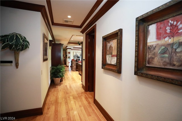 corridor with light hardwood / wood-style floors and crown molding