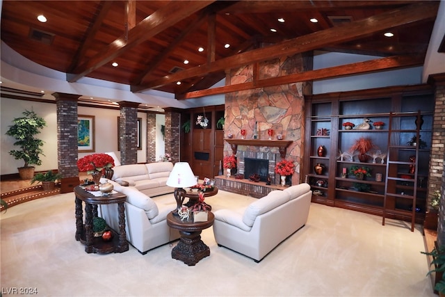 carpeted living room featuring a stone fireplace, ornate columns, and beamed ceiling