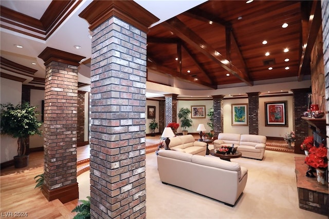 living room with brick wall, ornate columns, and beam ceiling