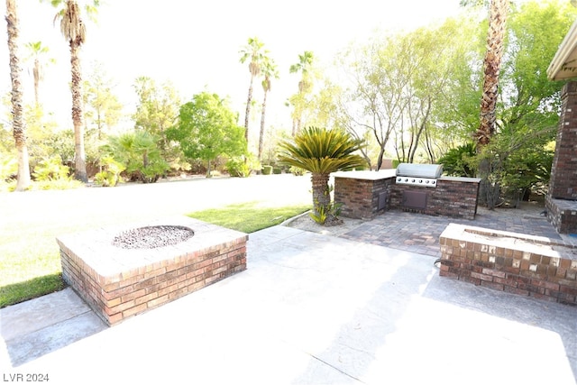 view of terrace featuring a grill, a fire pit, and exterior kitchen