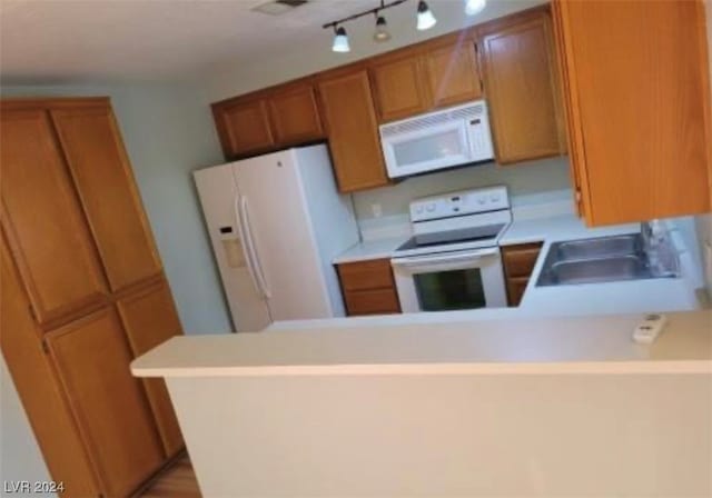 kitchen with sink, white appliances, kitchen peninsula, and track lighting