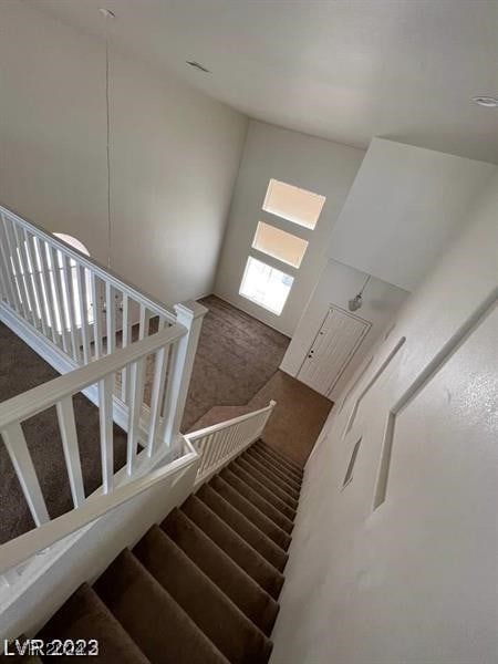 staircase with dark carpet and a high ceiling