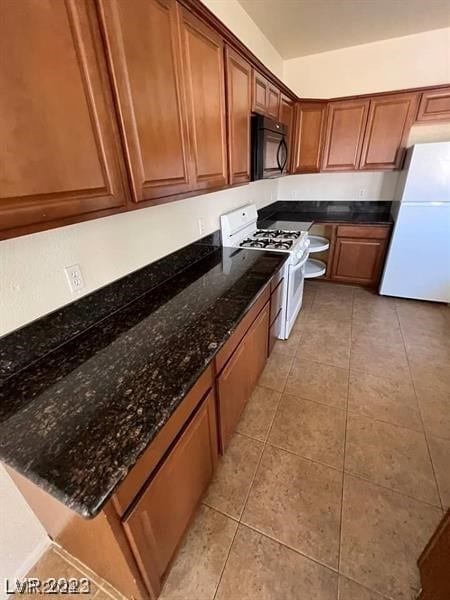 kitchen with white appliances, light tile floors, and dark stone counters