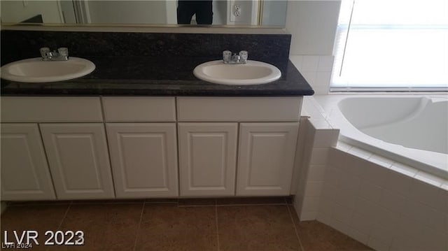 bathroom with dual bowl vanity, tile floors, and tiled tub