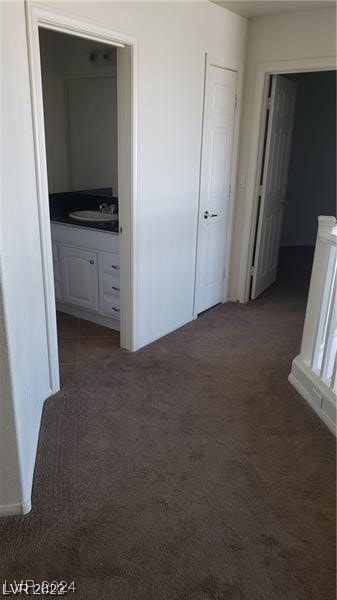 corridor with sink and dark colored carpet