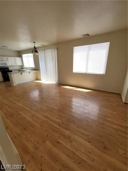 unfurnished living room with hardwood / wood-style flooring and an inviting chandelier