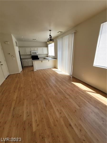 unfurnished living room with light hardwood / wood-style flooring and a chandelier