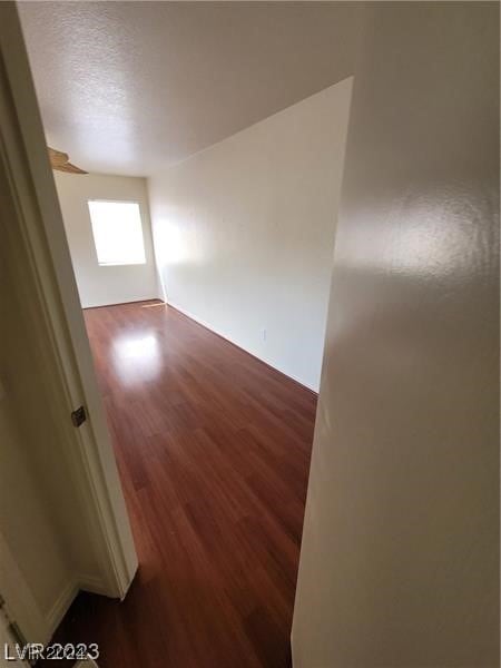 spare room featuring dark wood-type flooring and a textured ceiling