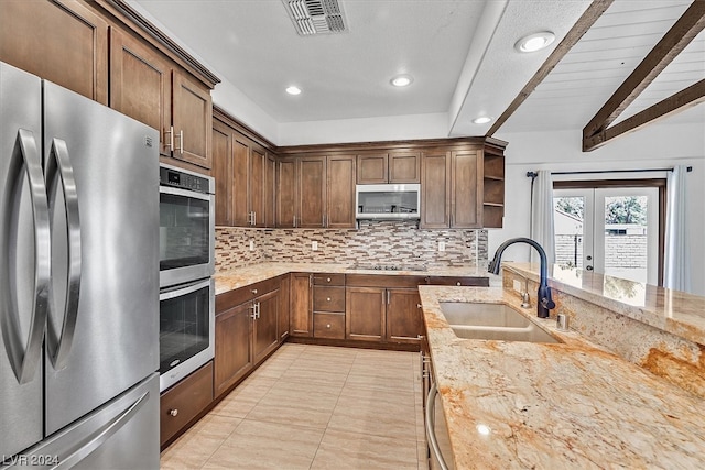 kitchen with sink, stainless steel appliances, beamed ceiling, and light stone counters