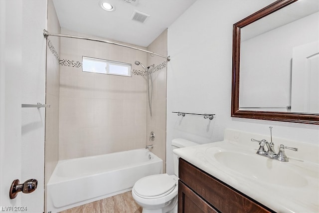 full bathroom featuring hardwood / wood-style flooring, vanity with extensive cabinet space, toilet, and tiled shower / bath