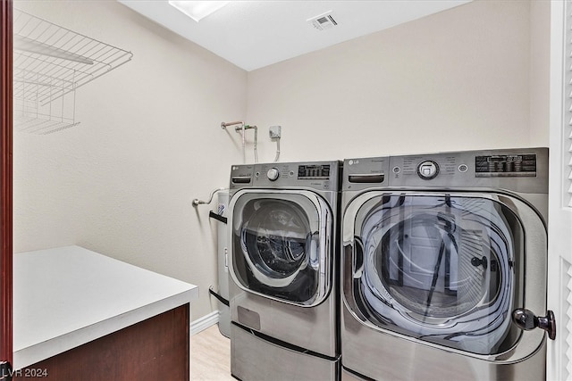 laundry area with light hardwood / wood-style floors and independent washer and dryer