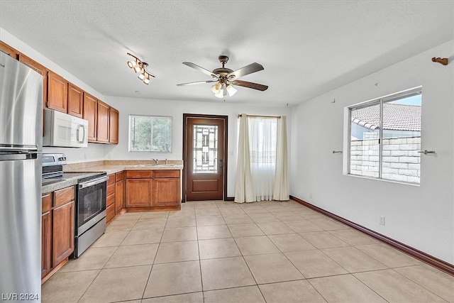 kitchen featuring ceiling fan, stainless steel appliances, light tile floors, a textured ceiling, and sink