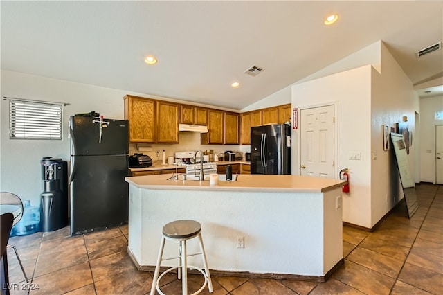 5717 Wizard Wand St, North Las Vegas, NV 89031 - kitchen with freestanding refrigerator, black refrigerator with ice dispenser, under cabinet range hood, a sink, and brown cabinets