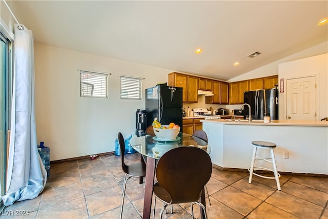 5717 Wizard Wand St, North Las Vegas, NV 89031 - kitchen featuring freestanding refrigerator, brown cabinets, stove, vaulted ceiling, and under cabinet range hood