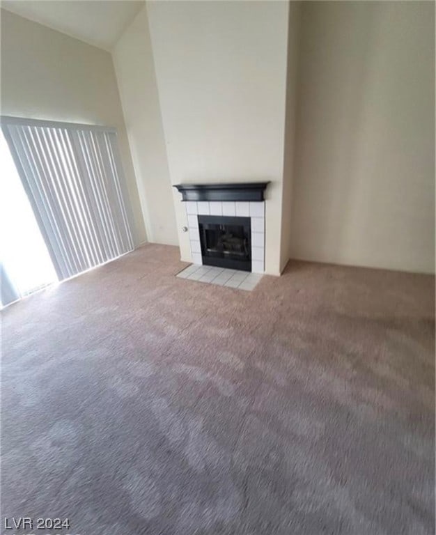 unfurnished living room with a tile fireplace and light colored carpet