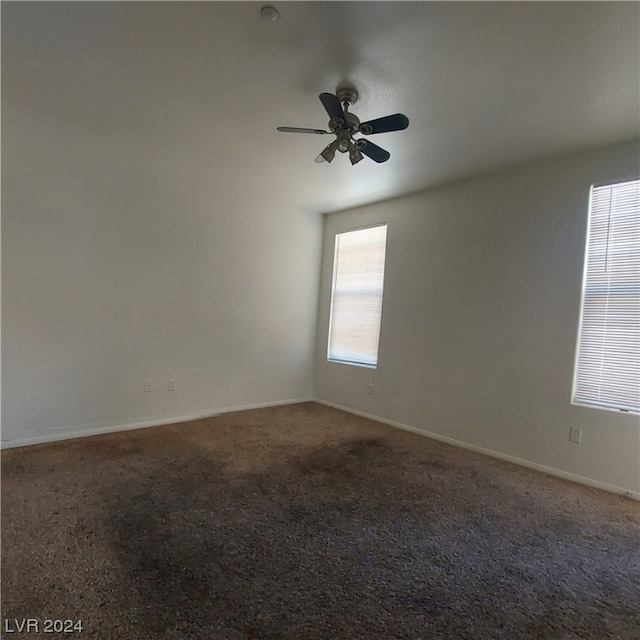 spare room featuring ceiling fan and dark carpet