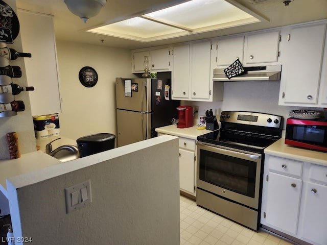 kitchen featuring appliances with stainless steel finishes, wall chimney range hood, light tile floors, and white cabinets