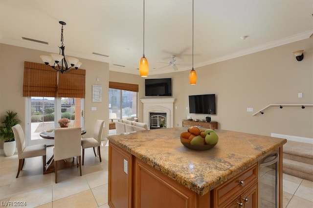 kitchen with light stone countertops, ceiling fan with notable chandelier, wine cooler, a kitchen island, and pendant lighting