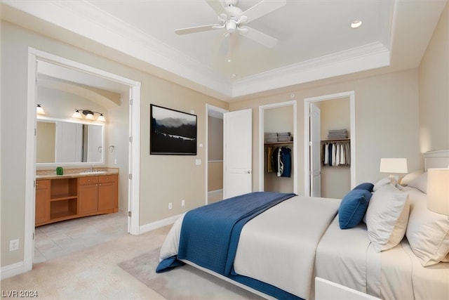 bedroom featuring connected bathroom, ceiling fan, a walk in closet, sink, and a raised ceiling