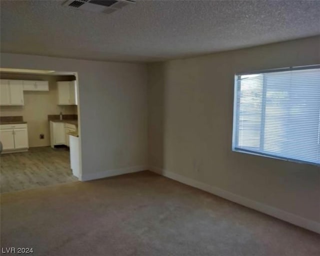 carpeted empty room with a textured ceiling