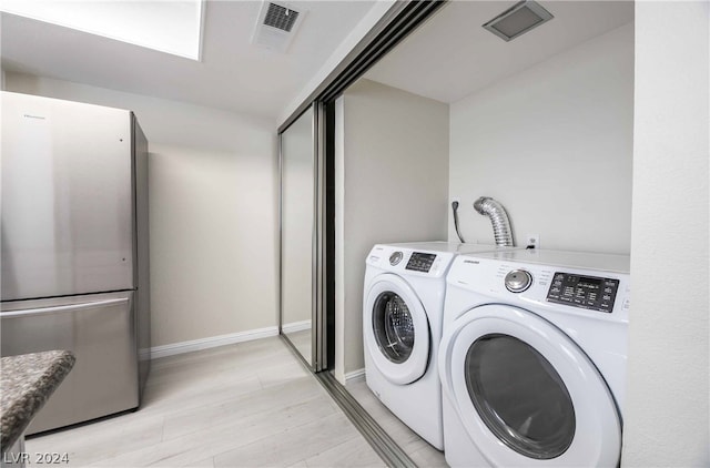 clothes washing area with independent washer and dryer and light wood-type flooring