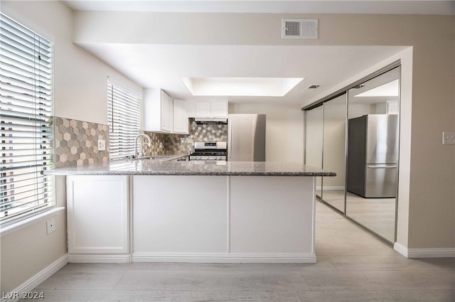 kitchen featuring stainless steel refrigerator, tasteful backsplash, white cabinetry, light stone countertops, and sink