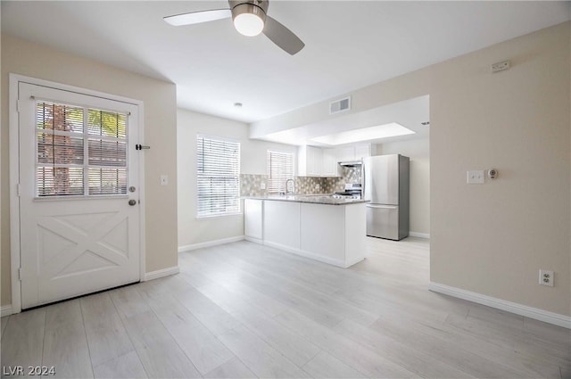 kitchen featuring stainless steel fridge, ceiling fan, backsplash, kitchen peninsula, and white cabinetry