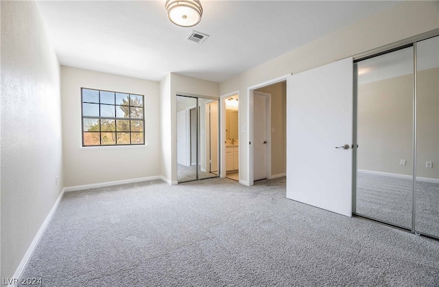 unfurnished bedroom with light carpet and two closets