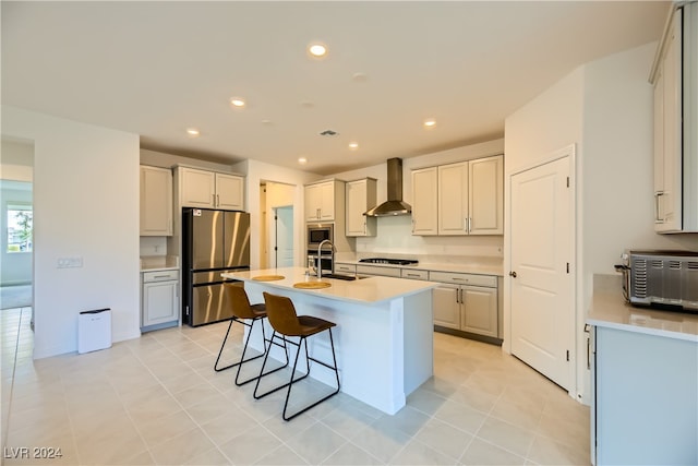 kitchen featuring stainless steel appliances, a kitchen island with sink, sink, wall chimney range hood, and light tile patterned floors