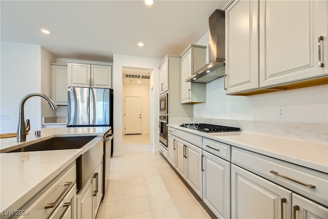 kitchen with white cabinetry, light stone counters, wall chimney range hood, and appliances with stainless steel finishes