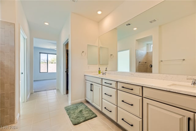 bathroom featuring a tile shower, tile patterned flooring, and vanity