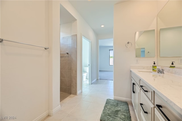 bathroom with tile patterned floors, vanity, toilet, and a tile shower