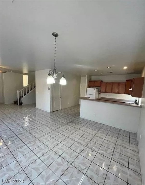 kitchen with light tile floors, a notable chandelier, hanging light fixtures, and white refrigerator