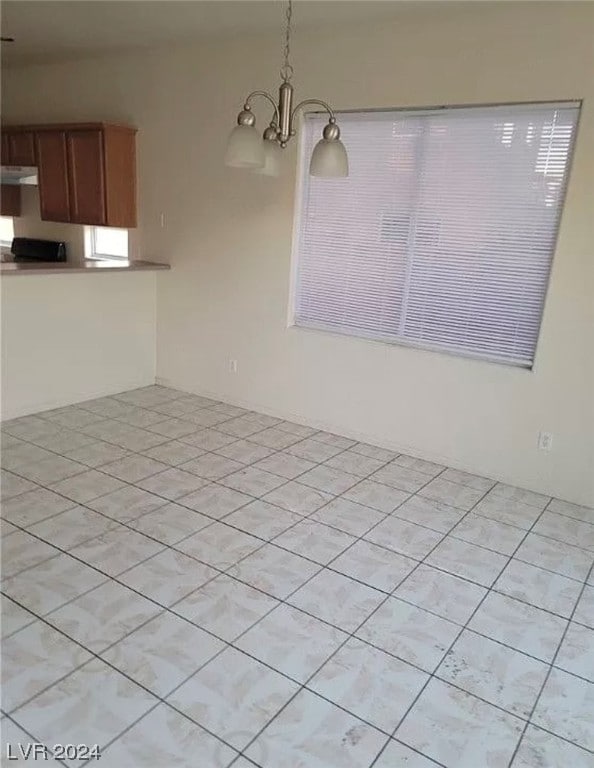 spare room with a notable chandelier and light tile floors