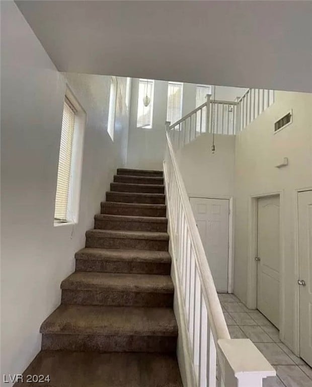 staircase featuring a high ceiling and light tile floors