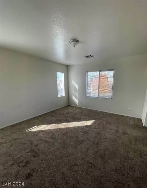 spare room with dark colored carpet and a textured ceiling