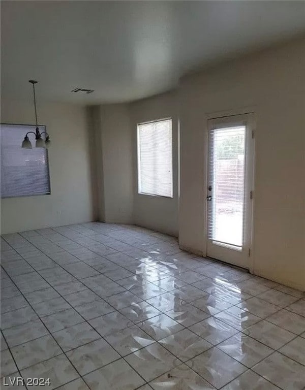 unfurnished room featuring an inviting chandelier and light tile floors