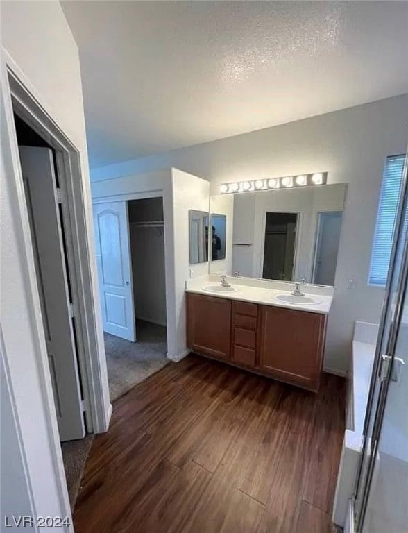 bathroom with a textured ceiling, wood-type flooring, double sink, and large vanity